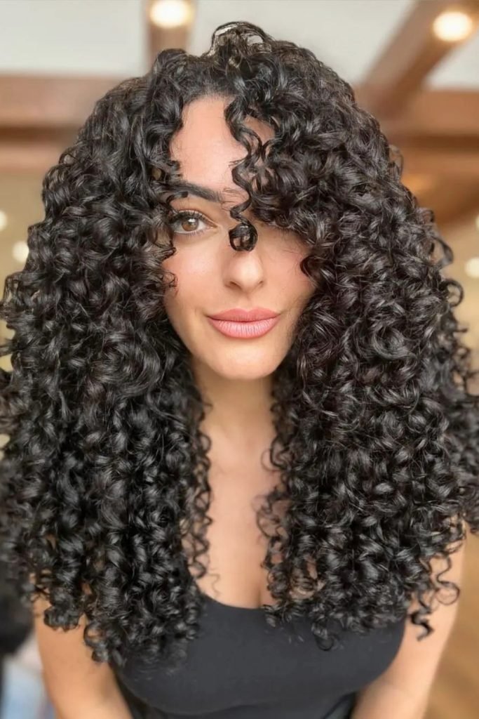 Voluminous Curls with Wispy Bangs Hairstyle